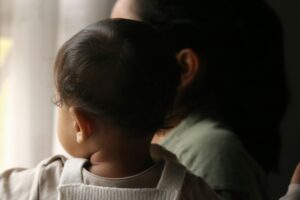 Mother holding her baby near a window during the postpartum period