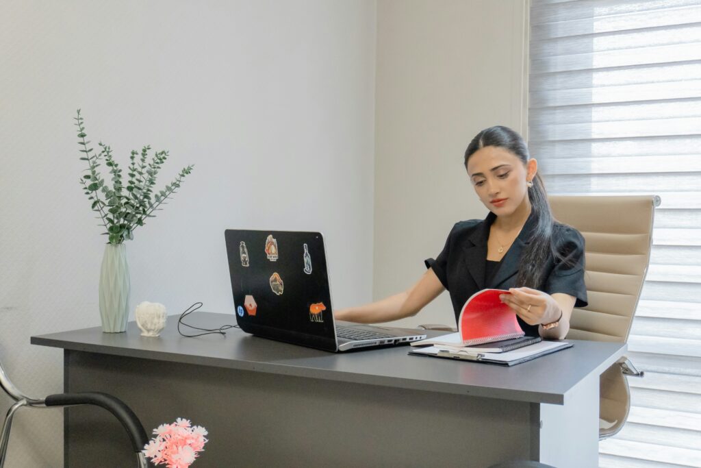Woman reviewing documents while working at a laptop.