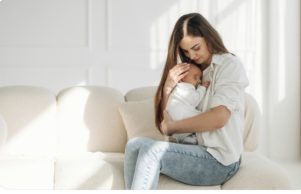 Mother holding her newborn baby while sitting at home.